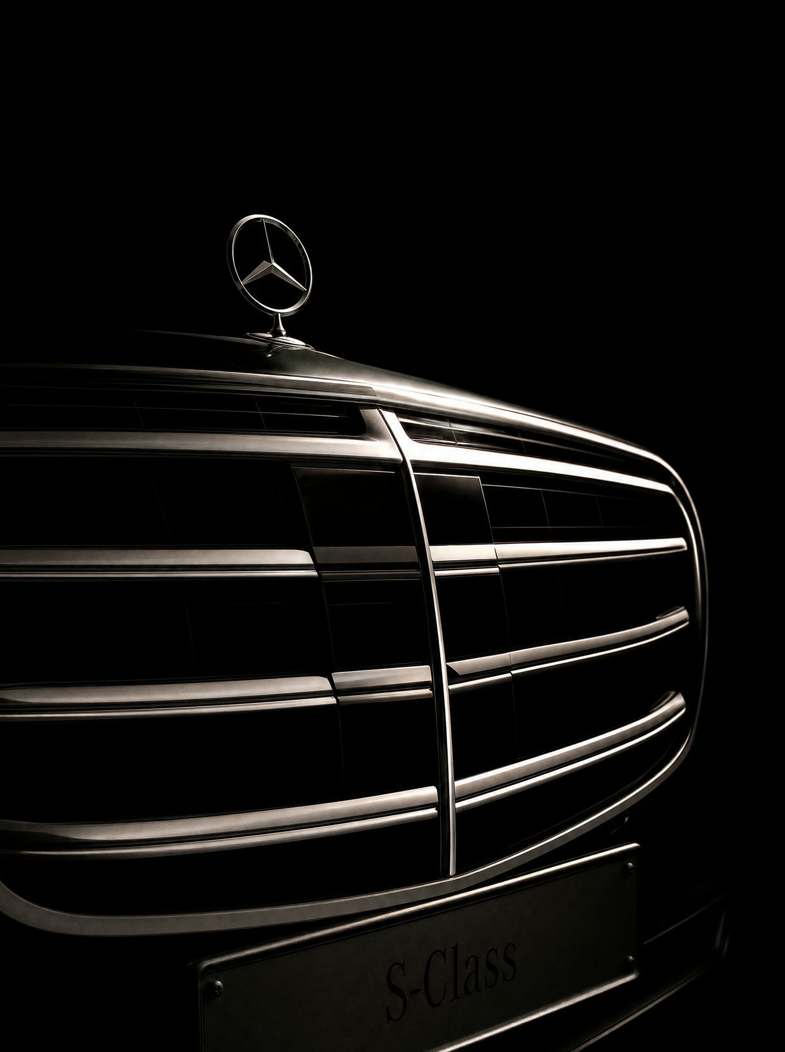 Macro detail of the Mercedes-Benz S-Class chrome grille and Mercedes star under low, controlled light